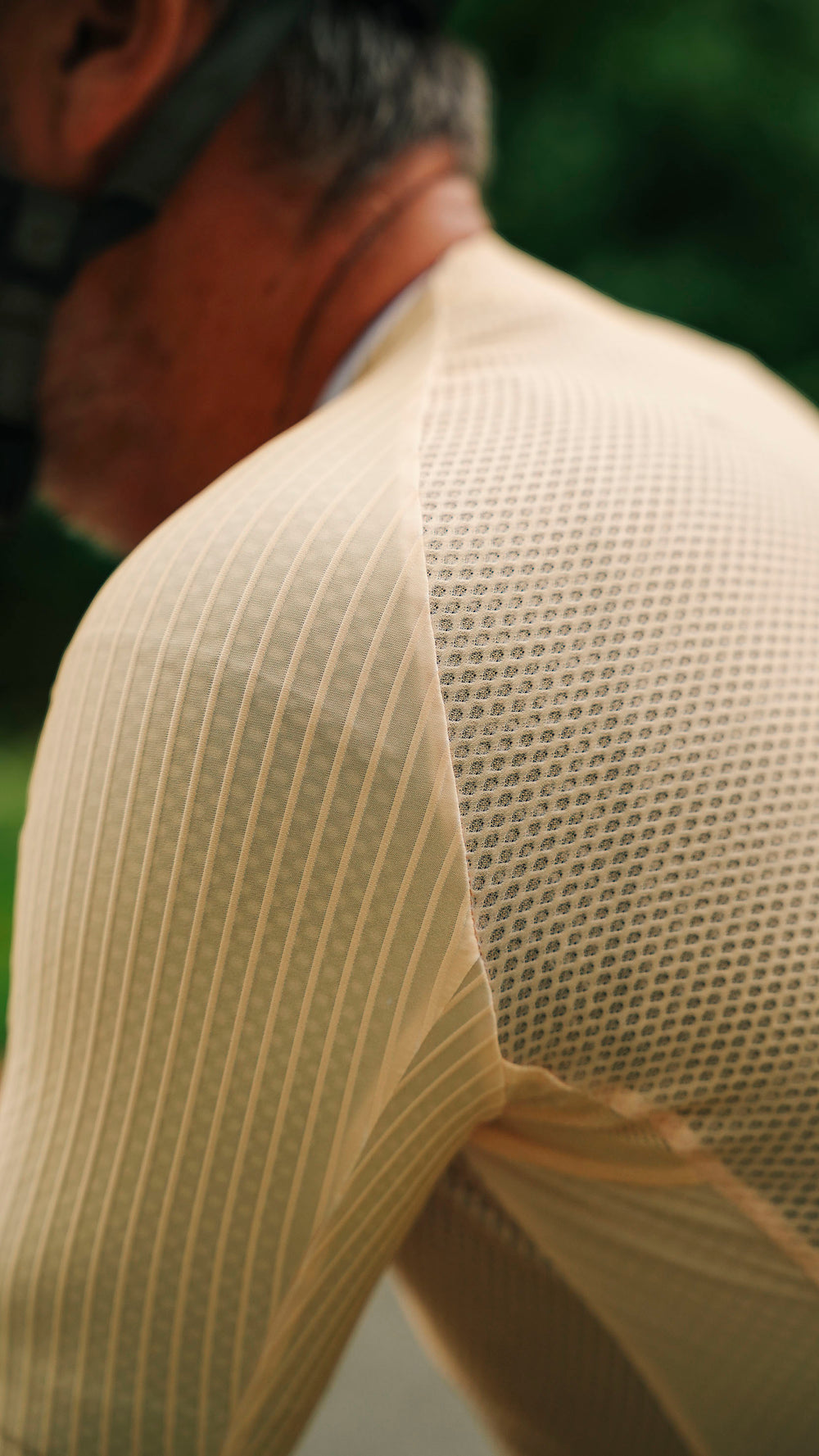 Close-up of a person outdoors wearing a light  ribbed knit shirt with a textured mesh back panel.