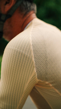 Close-up of a person outdoors wearing a light  ribbed knit shirt with a textured mesh back panel.